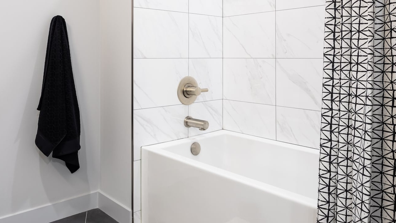 Bathroom at 330 S Wells Apartments in Chicago with white tiled tub, shower, and modern fixtures