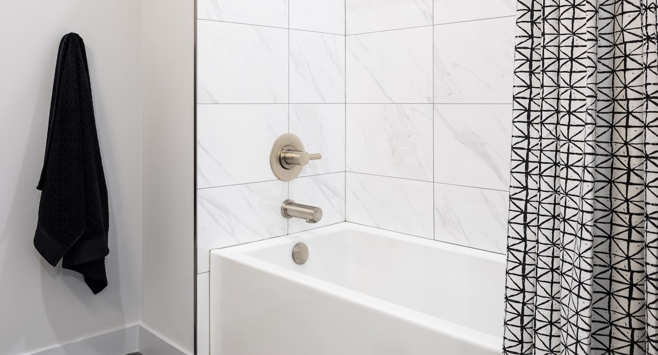 Bathroom at 330 S Wells Apartments in Chicago with white tiled tub, shower, and modern fixtures