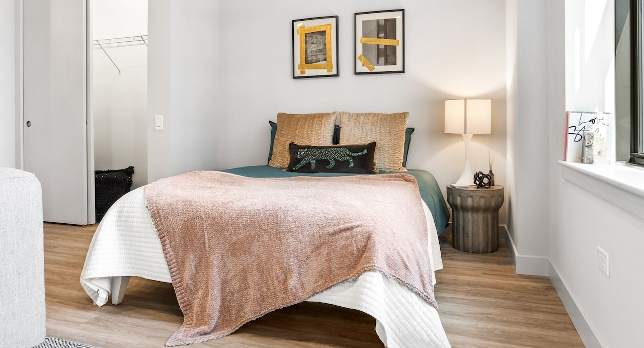 Bright bedroom at 330 S Wells Apartments in Chicago featuring a cozy bed, nightstand, and natural light from large window