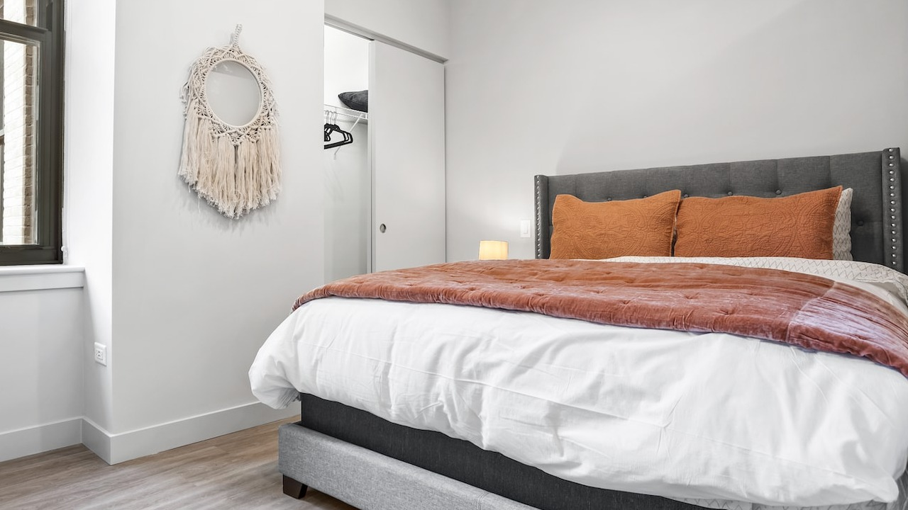 Cozy bedroom at 330 S Wells Apartments in Chicago featuring a gray bed frame, large window, and neutral modern décor