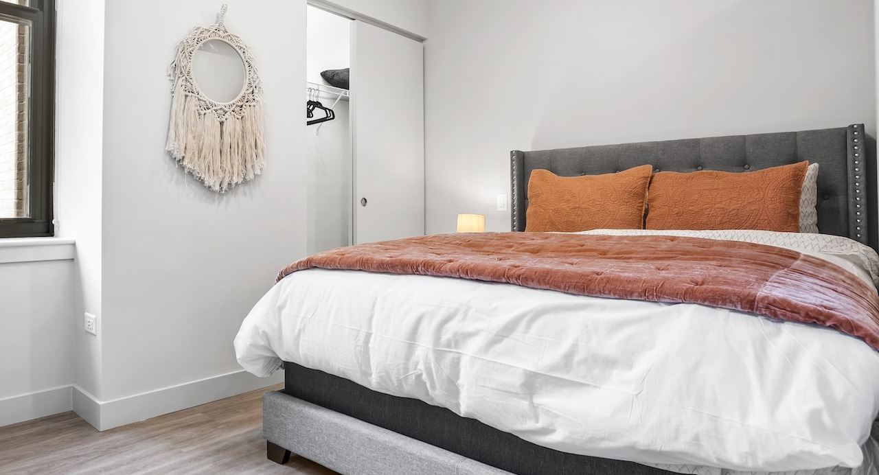 Cozy bedroom at 330 S Wells Apartments in Chicago featuring a gray bed frame, large window, and neutral modern décor