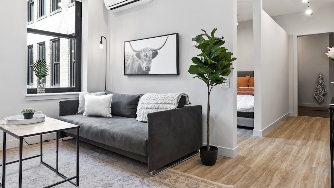 Bright living room at 330 S Wells Apartments in Chicago featuring a gray sofa, modern décor, large window, and natural light