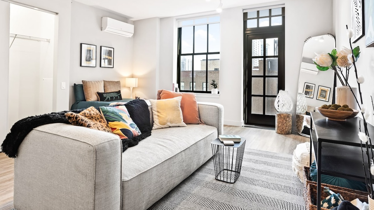 Cozy studio living space at 330 S Wells Apartments in Chicago with sofa, colorful pillows, and natural light from windows