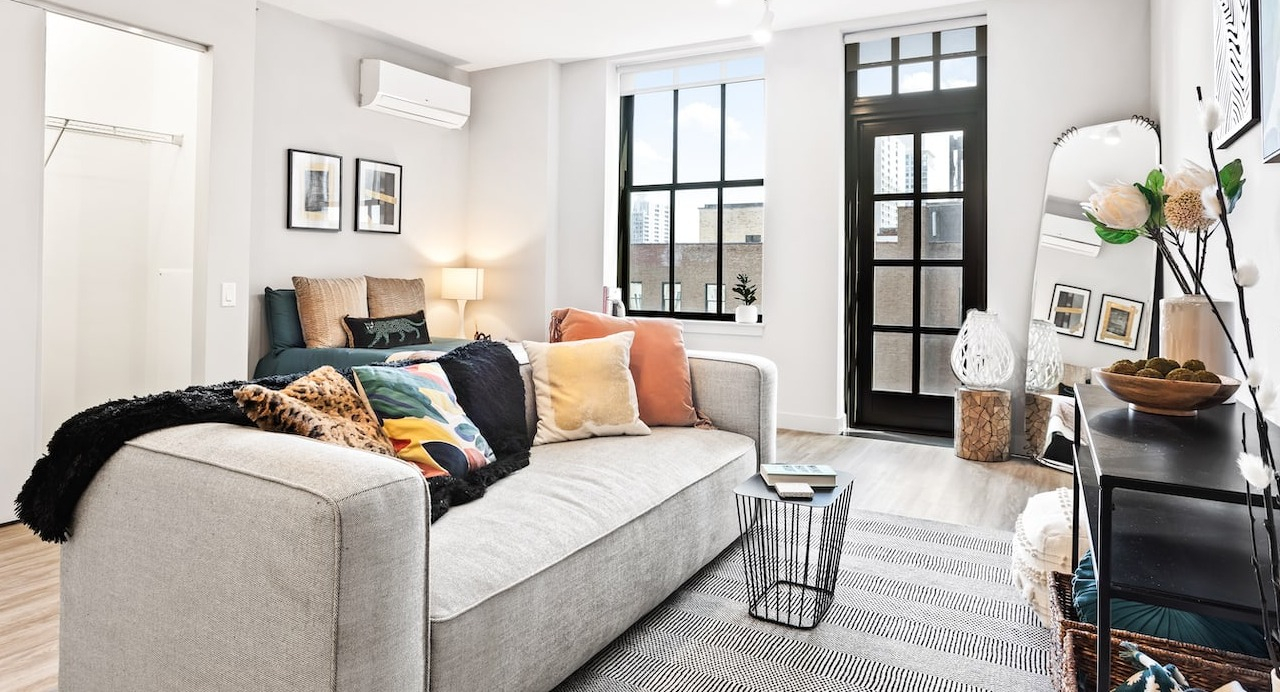 Cozy studio living space at 330 S Wells Apartments in Chicago with sofa, colorful pillows, and natural light from windows