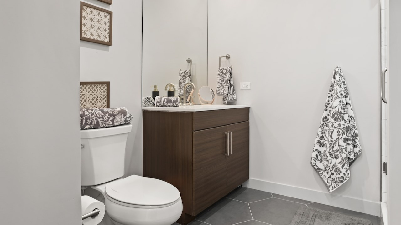 Modern bathroom at 330 S Wells Apartments in Chicago with wood vanity, large mirror, and sleek tile flooring
