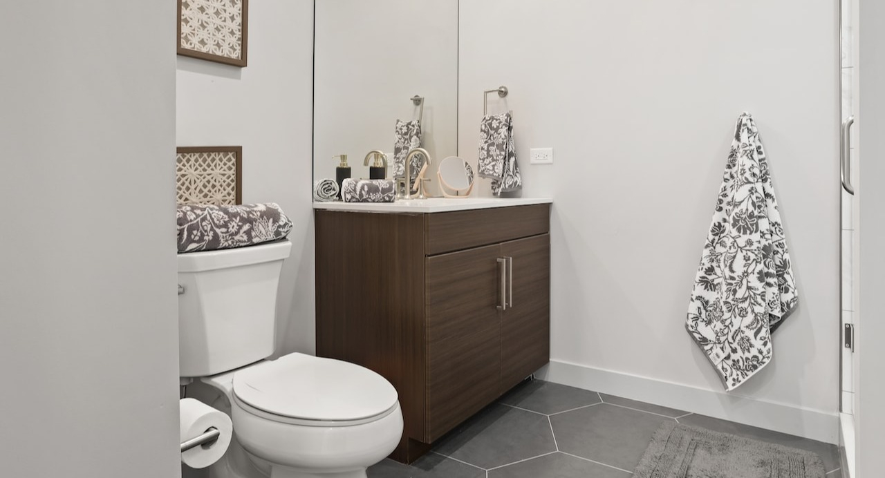 Modern bathroom at 330 S Wells Apartments in Chicago with wood vanity, large mirror, and sleek tile flooring