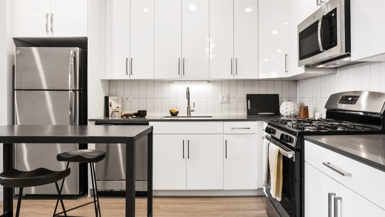Sleek modern kitchen at 330 S Wells Apartments in Chicago with white cabinets, stainless steel appliances, and wood floors