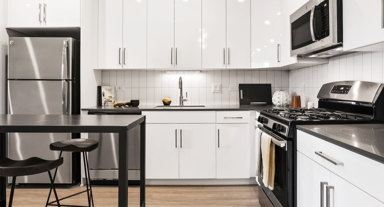 Sleek modern kitchen at 330 S Wells Apartments in Chicago with white cabinets, stainless steel appliances, and wood floors