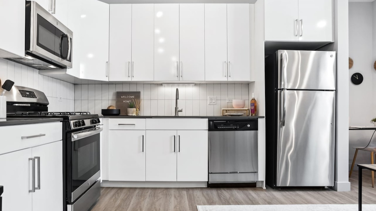 Modern kitchen at 330 S Wells Apartments in Chicago with stainless steel appliances, white cabinets, and wood flooring