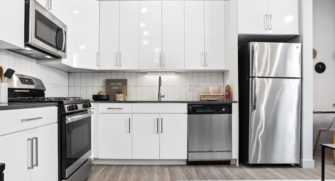 Modern kitchen at 330 S Wells Apartments in Chicago with stainless steel appliances, white cabinets, and wood flooring