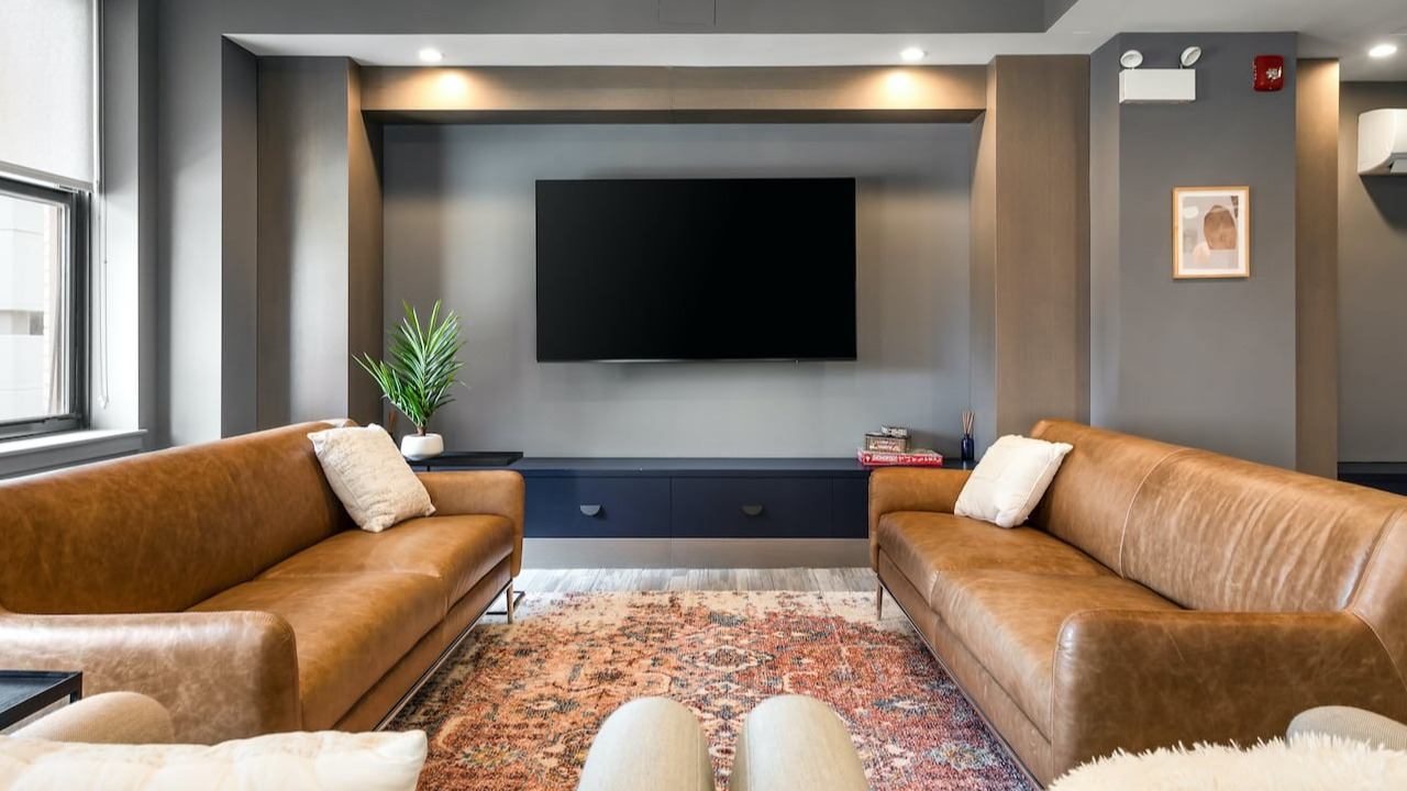 Resident lounge at 330 S Wells Apartments in Chicago featuring leather sofas, flat-screen TV, and cozy décor