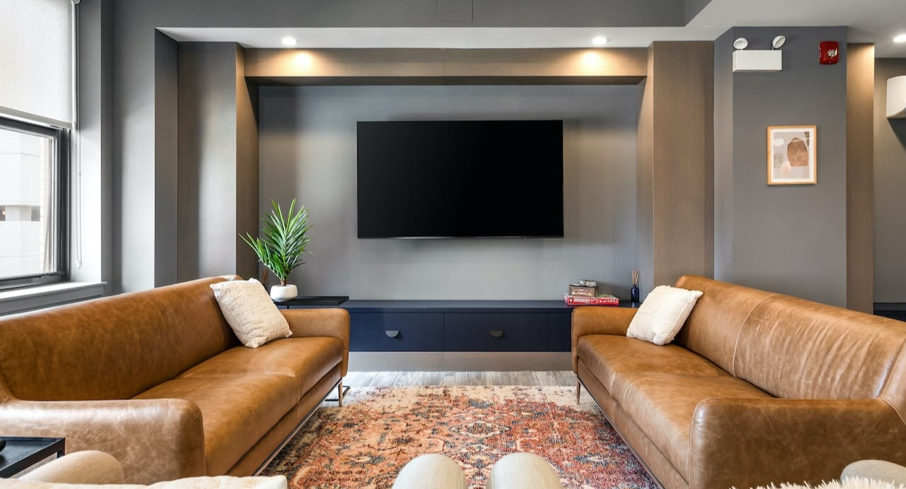 Resident lounge at 330 S Wells Apartments in Chicago featuring leather sofas, flat-screen TV, and cozy décor