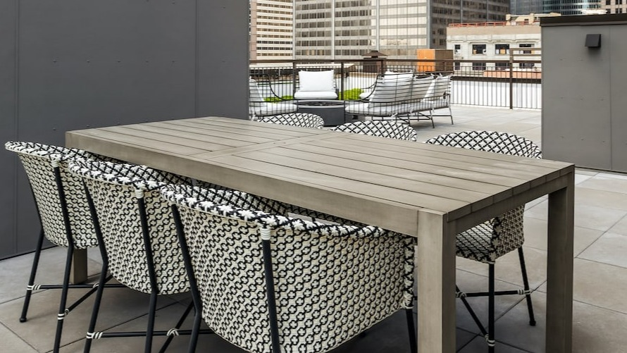 Rooftop dining area at 330 S Wells Apartments in Chicago with table, chairs, string lights, and city views