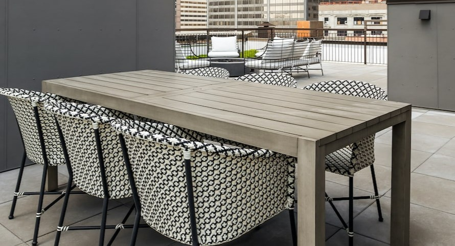 Rooftop dining area at 330 S Wells Apartments in Chicago with table, chairs, string lights, and city views