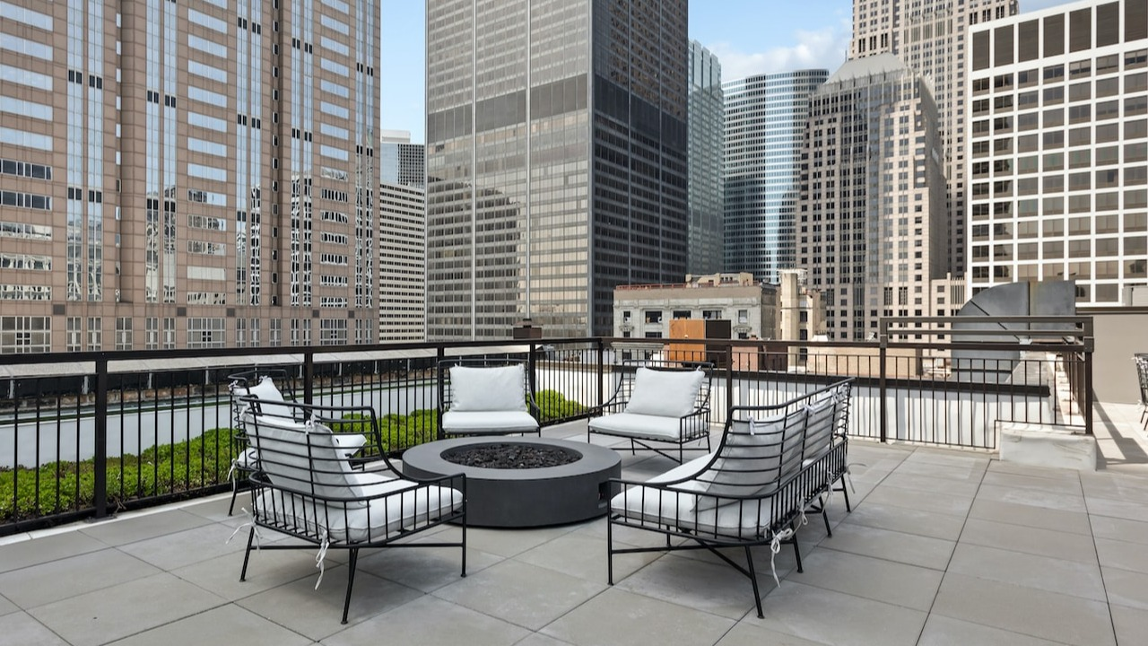 Rooftop firepit lounge at 330 S Wells Apartments in Chicago with cushioned seating and city skyline views