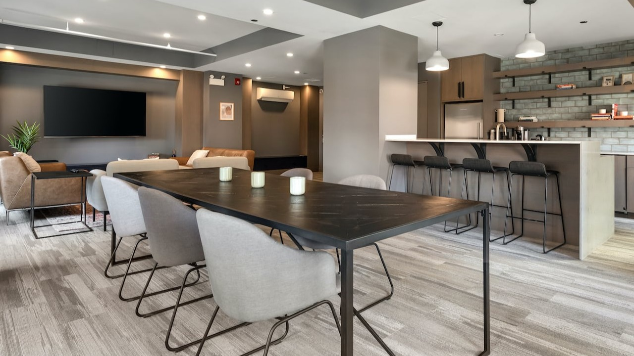 Spacious resident lounge at 330 S Wells Apartments in Chicago with dining table, lounge seating, and modern kitchen