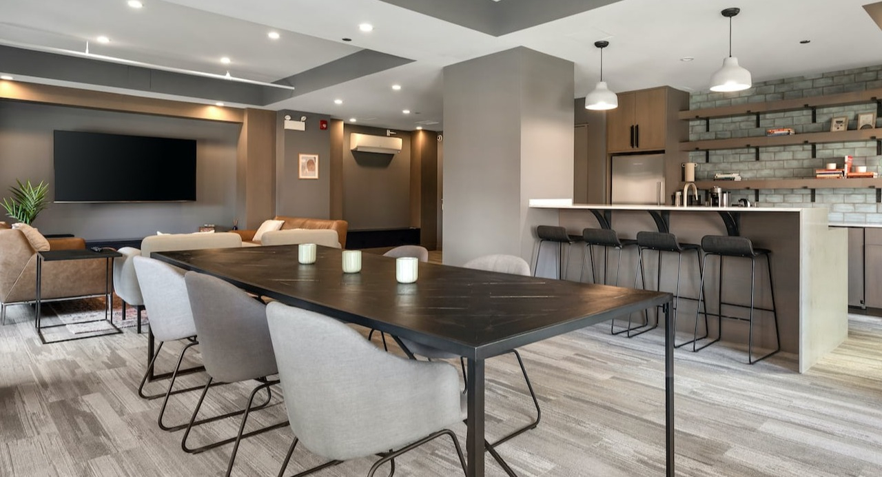 Spacious resident lounge at 330 S Wells Apartments in Chicago with dining table, lounge seating, and modern kitchen