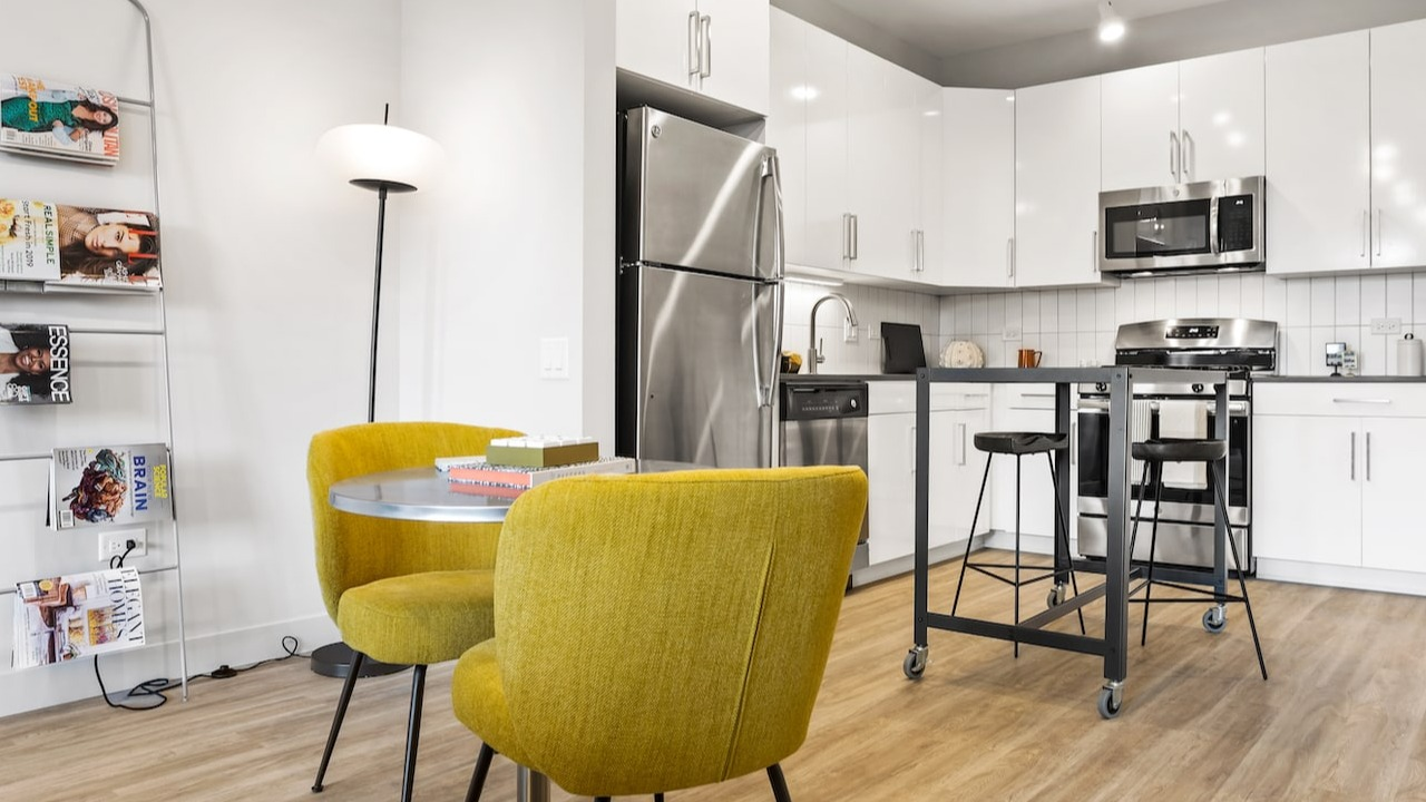 Studio apartment kitchen and dining area at 330 S Wells Apartments in Chicago with stainless steel appliances and yellow chairs