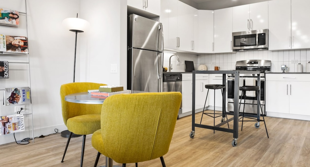 Studio apartment kitchen and dining area at 330 S Wells Apartments in Chicago with stainless steel appliances and yellow chairs