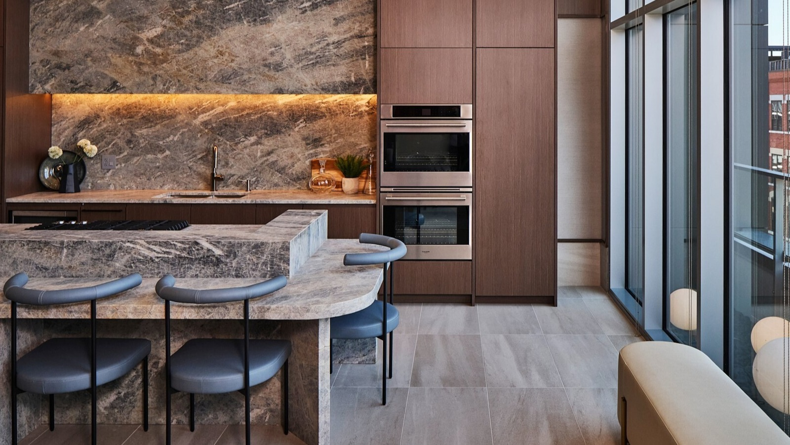 Chef’s kitchen with dramatic stone counters, double ovens, and tall windows in the resident lounge at 369 Grand apartments in Chicago