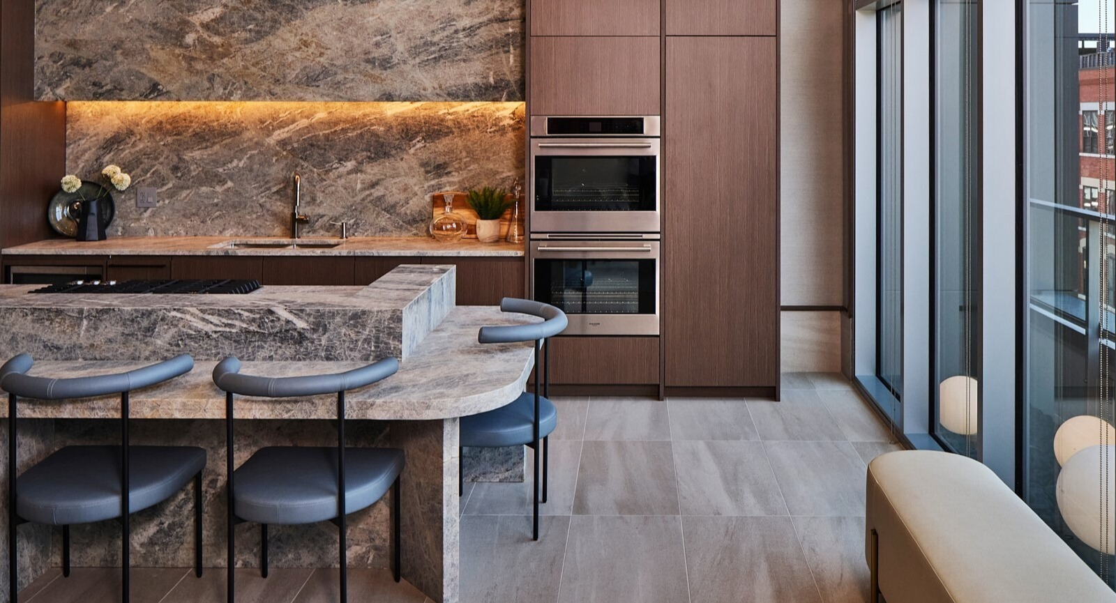 Chef’s kitchen with dramatic stone counters, double ovens, and tall windows in the resident lounge at 369 Grand apartments in Chicago