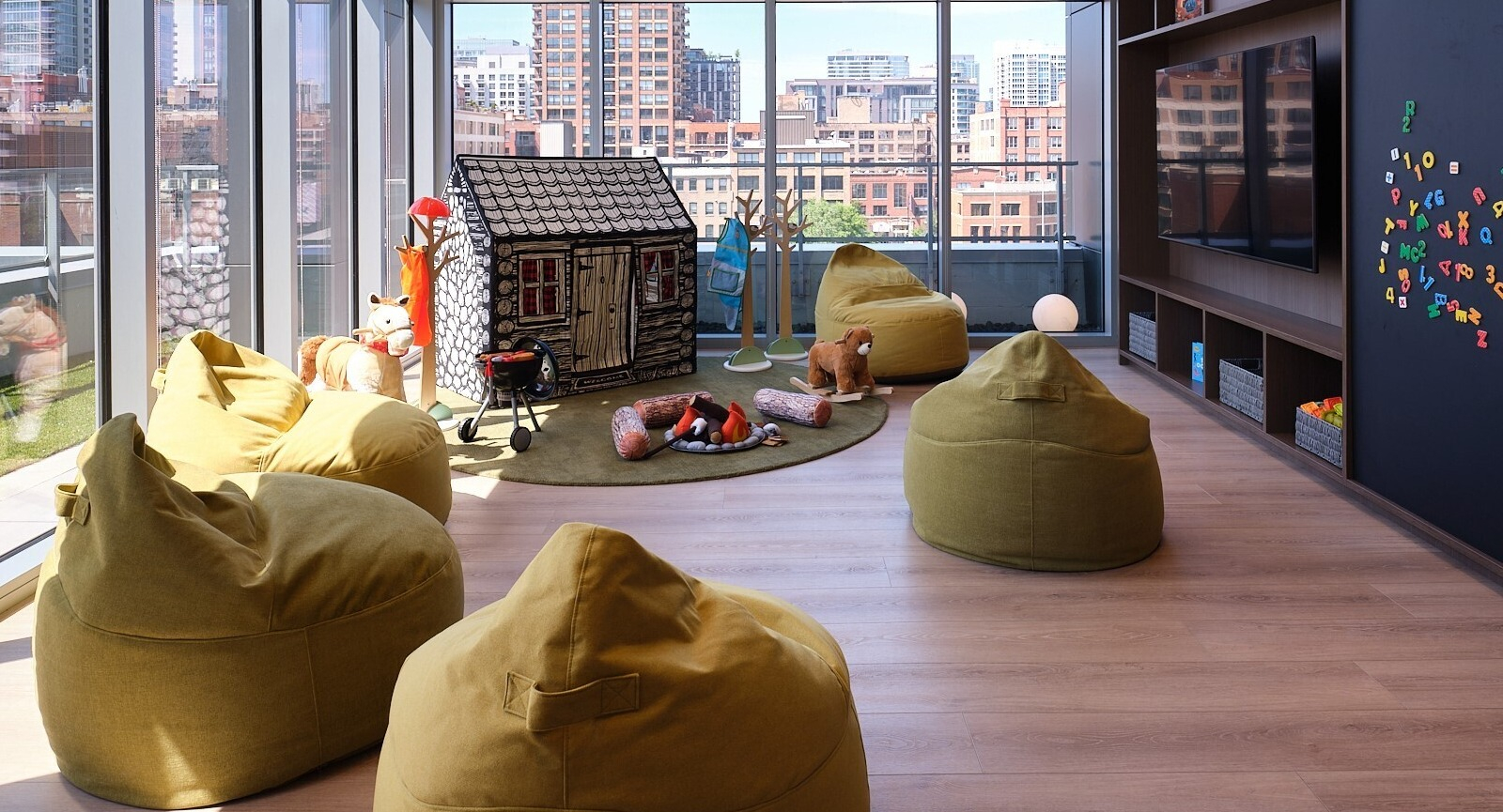 Children’s playroom with beanbag seating, playhouse, toys, and skyline views through tall windows at 369 Grand apartments in Chicago