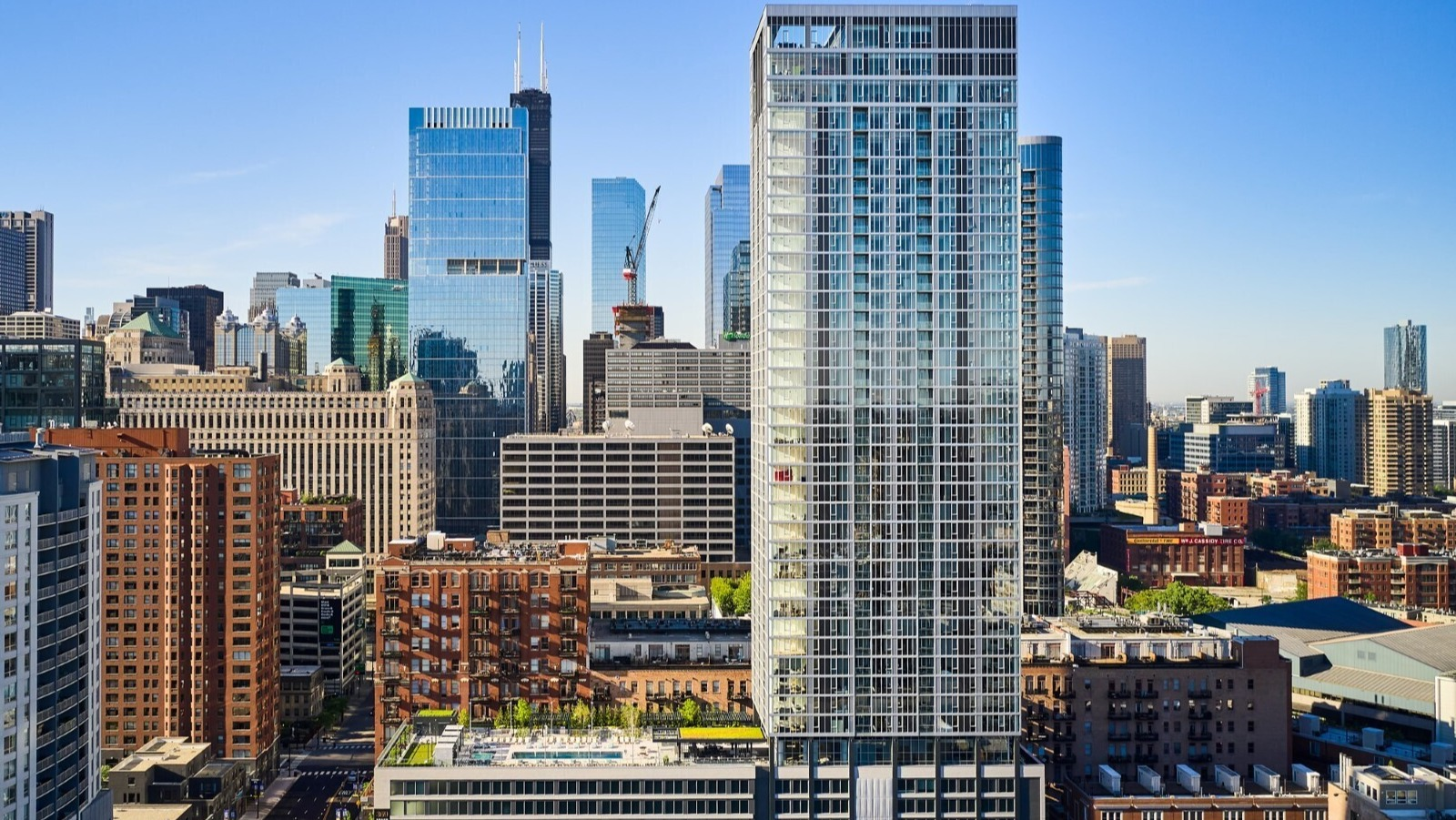 Aerial view of 369 Grand high-rise with rooftop amenities, set against the downtown Chicago skyline near River North and Fulton Market