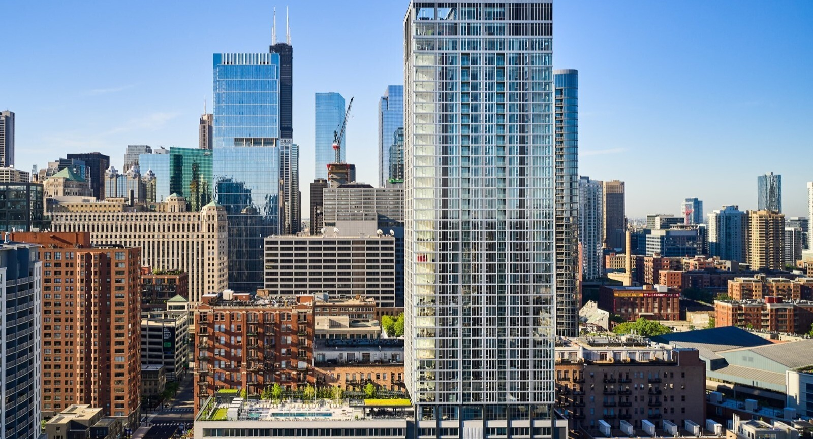 Aerial view of 369 Grand high-rise with rooftop amenities, set against the downtown Chicago skyline near River North and Fulton Market