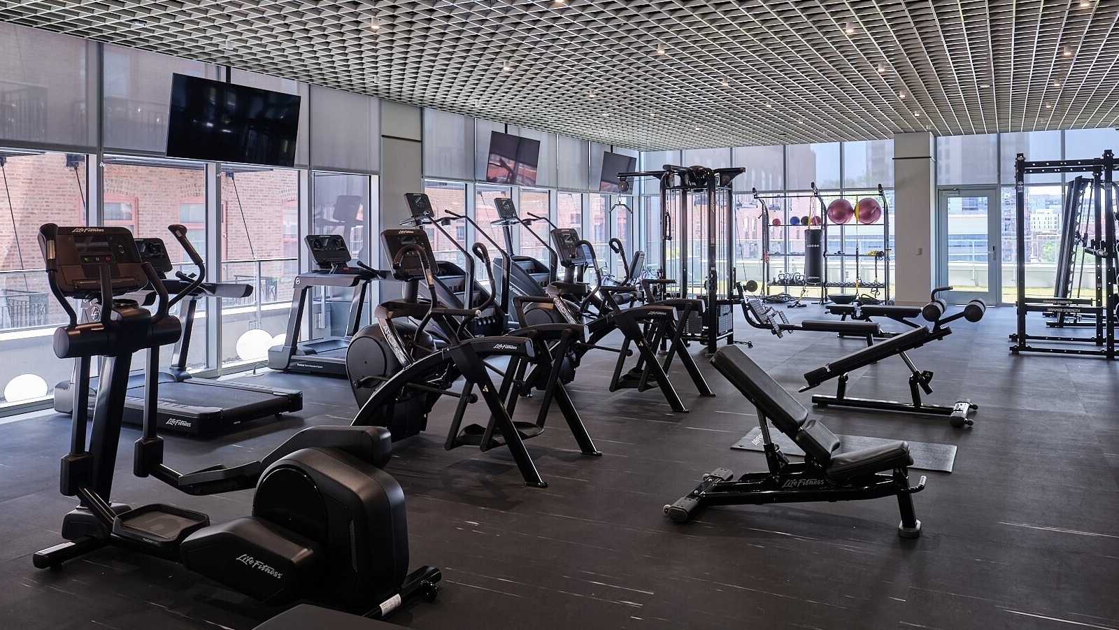 Spacious fitness center with cardio machines, weight training equipment, and wall-to-wall windows at 369 Grand apartments in Chicago