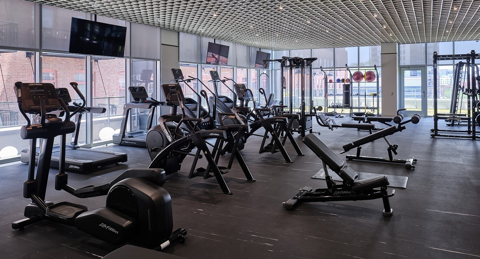Spacious fitness center with cardio machines, weight training equipment, and wall-to-wall windows at 369 Grand apartments in Chicago