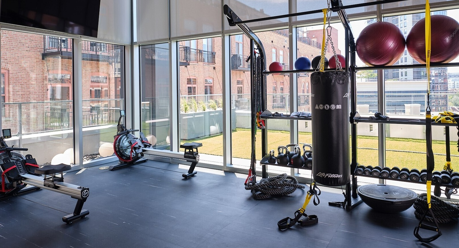 Functional training zone with squat rack, kettlebells, medicine balls, rowing machines, and a heavy bag at 369 Grand apartments in Chicago