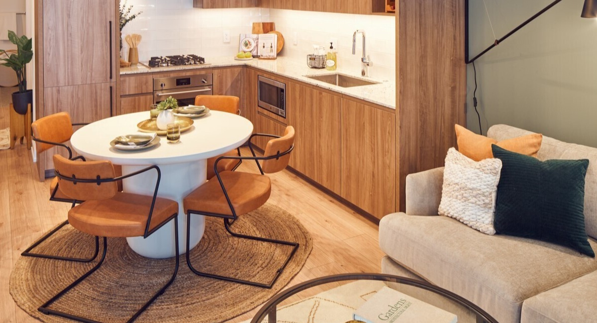 Modern L-shaped kitchen with integrated appliances, stone countertops, and an oval dining set at 369 Grand apartments in Chicago