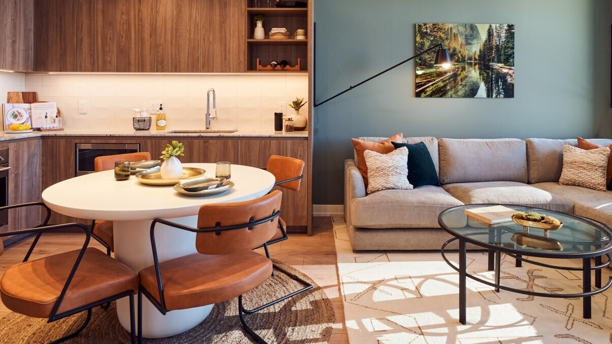 Open-concept kitchen and living space with warm wood cabinetry, round dining table, and comfy sectional at 369 Grand apartments in Chicago