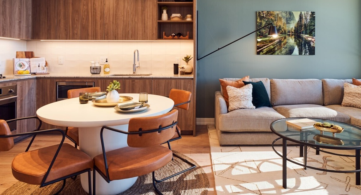 Open-concept kitchen and living space with warm wood cabinetry, round dining table, and comfy sectional at 369 Grand apartments in Chicago