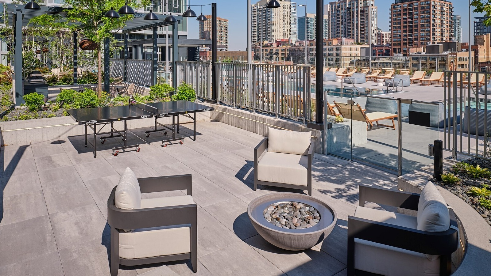 Outdoor lounge with modern fire pit seating, ping pong table, and access to the pool deck at 369 Grand apartments in Chicago