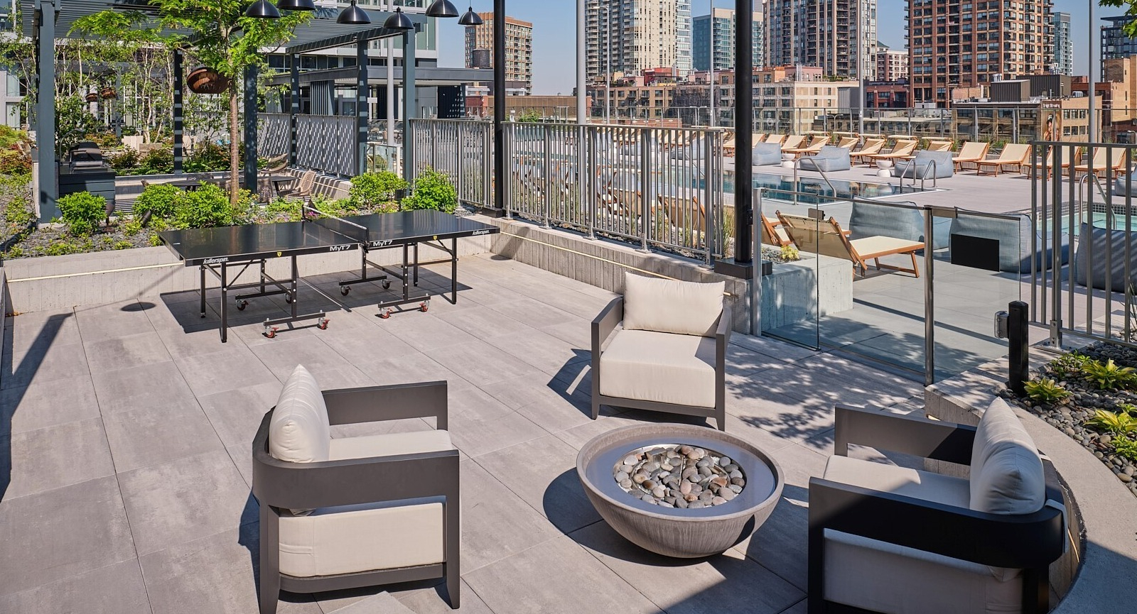 Outdoor lounge with modern fire pit seating, ping pong table, and access to the pool deck at 369 Grand apartments in Chicago