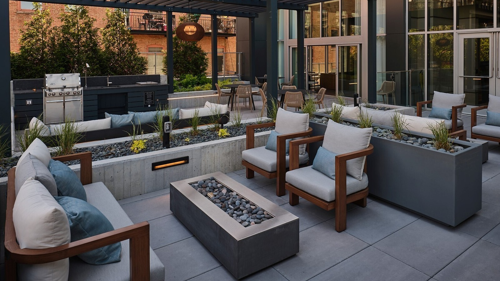 Outdoor lounge with pergola shade, grilling station, cushioned seating, and linear fire features at 369 Grand apartments in Chicago