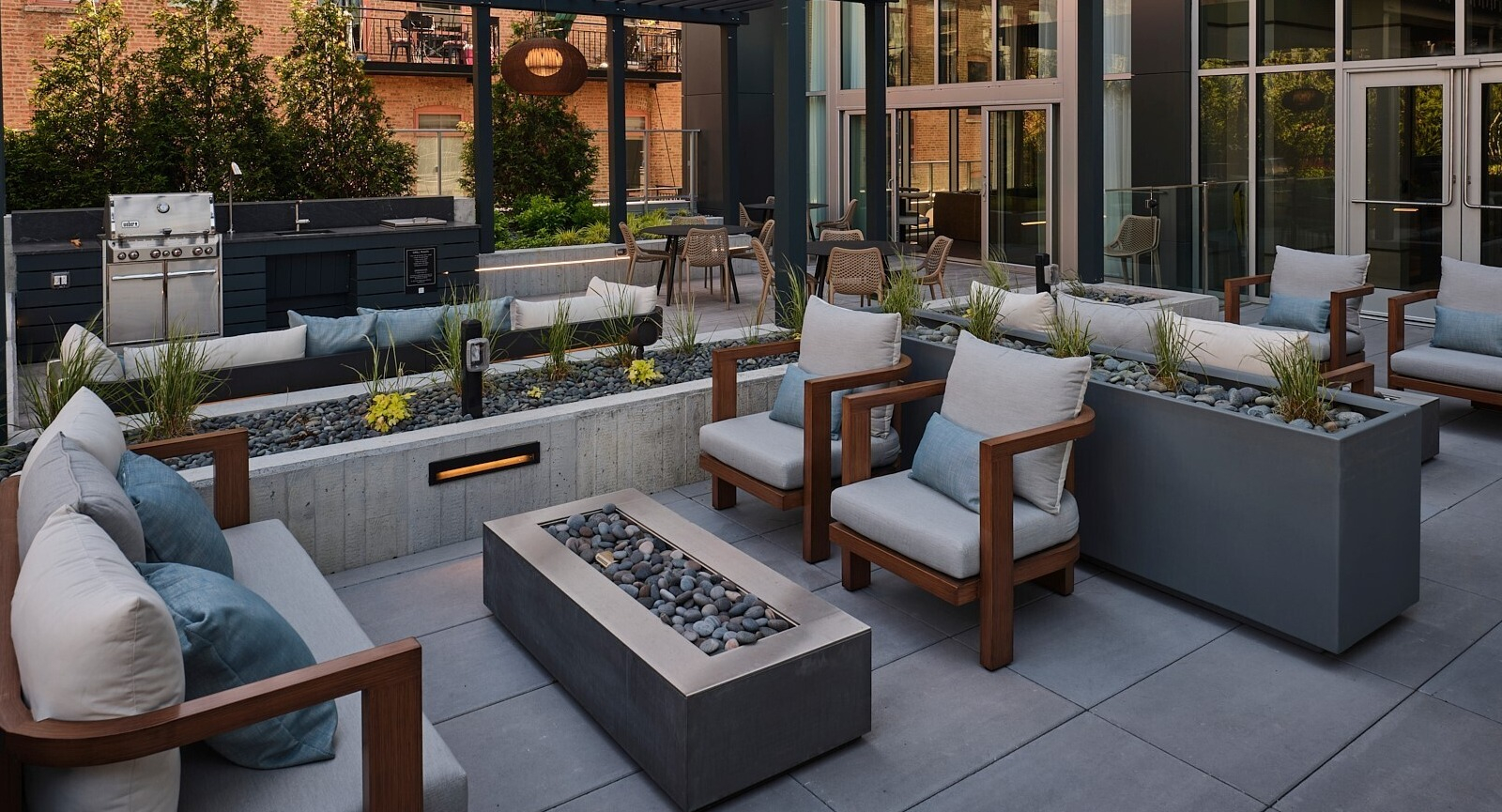 Outdoor lounge with pergola shade, grilling station, cushioned seating, and linear fire features at 369 Grand apartments in Chicago