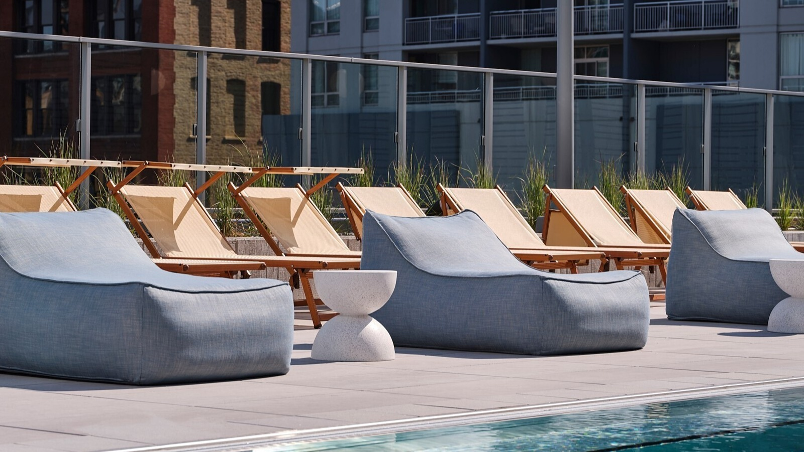 Poolside setup with fabric loungers, side tables, and classic sling chairs along the sunny sundeck at 369 Grand apartments in Chicago