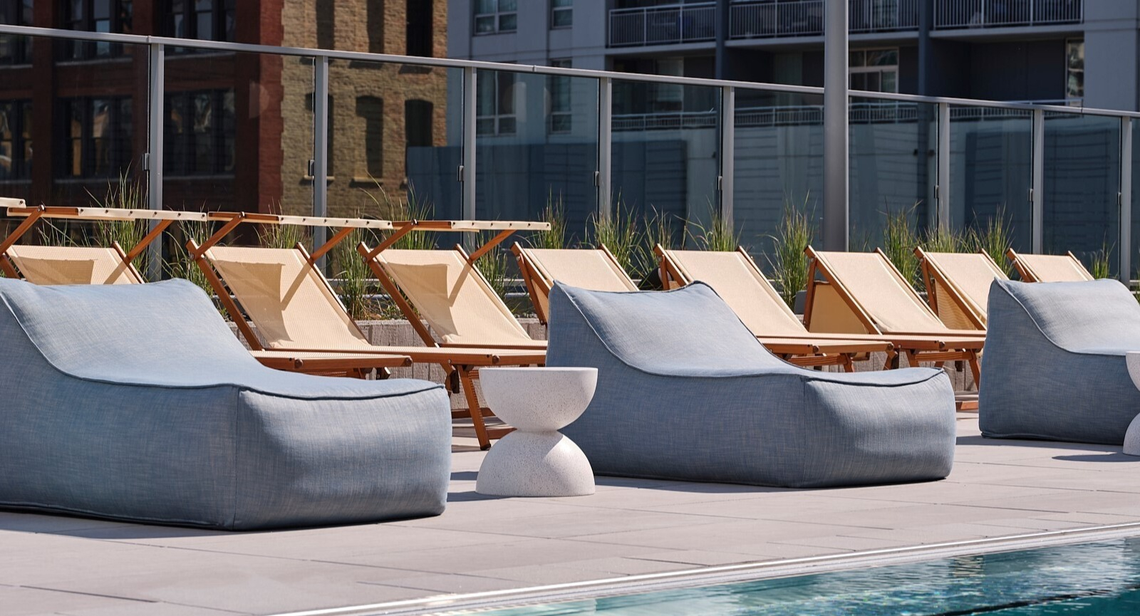Poolside setup with fabric loungers, side tables, and classic sling chairs along the sunny sundeck at 369 Grand apartments in Chicago