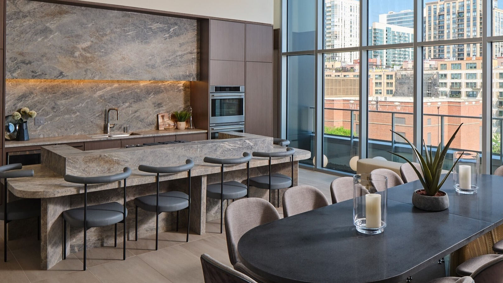 Elegant resident dining room with a chef’s kitchen, stone island, and long table framed by floor-to-ceiling windows at 369 Grand in Chicago