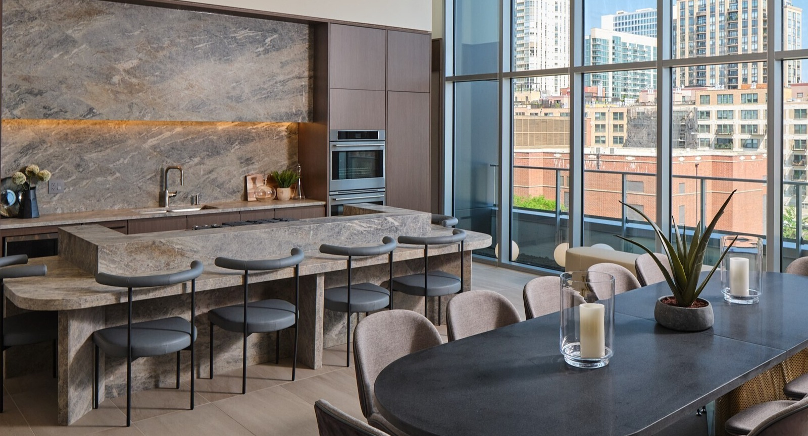 Elegant resident dining room with a chef’s kitchen, stone island, and long table framed by floor-to-ceiling windows at 369 Grand in Chicago