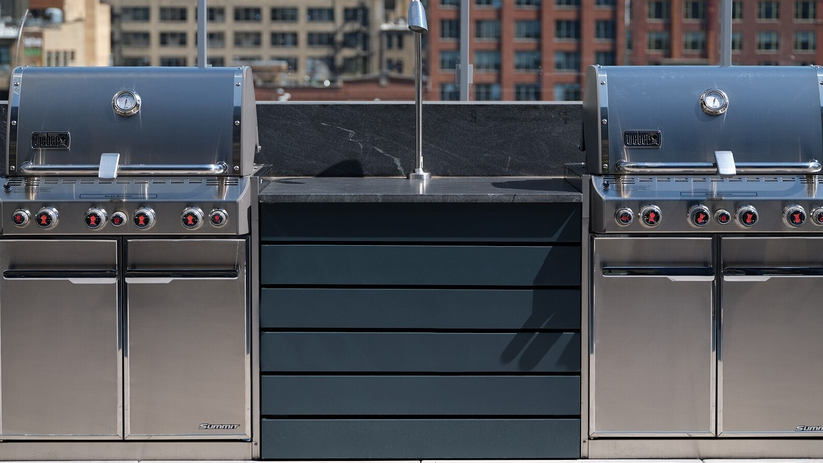 Stainless steel grilling stations with prep counters on a rooftop terrace with city views at 369 Grand apartments in Chicago
