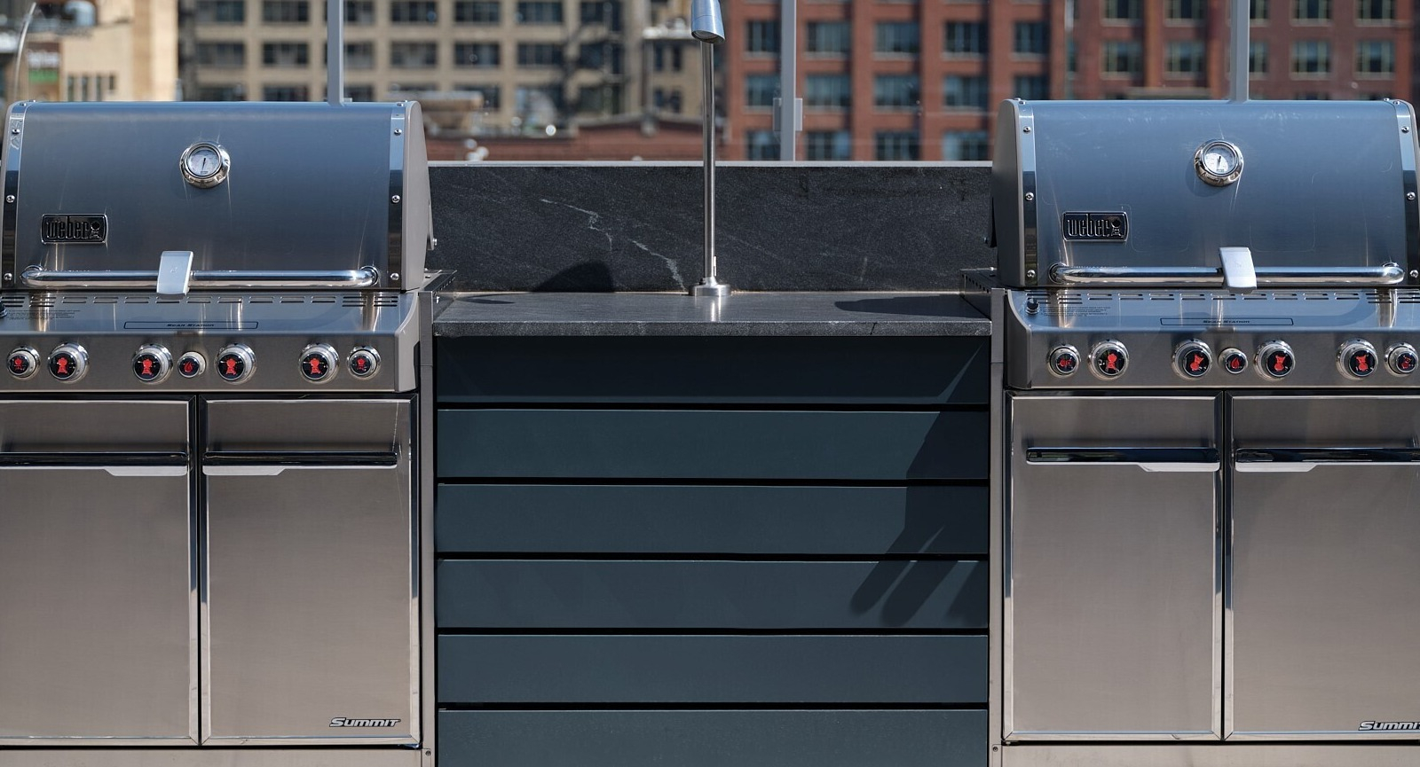 Stainless steel grilling stations with prep counters on a rooftop terrace with city views at 369 Grand apartments in Chicago