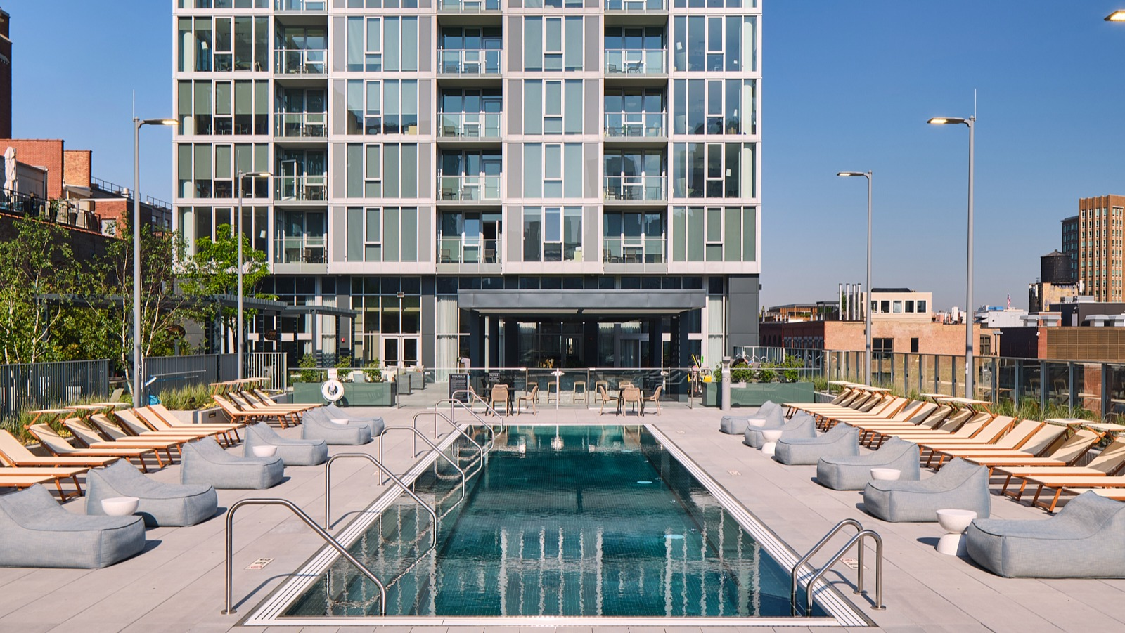 Rooftop sundeck with lap pool, rows of loungers, and open city skyline backdrop at 369 Grand apartments in Chicago