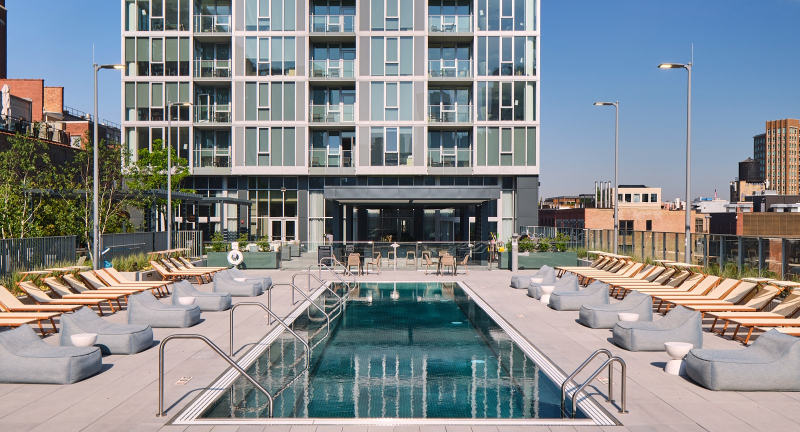 Rooftop sundeck with lap pool, rows of loungers, and open city skyline backdrop at 369 Grand apartments in Chicago