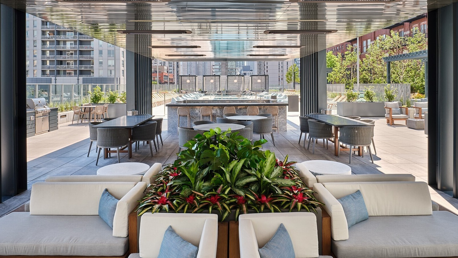 Shaded outdoor pavilion with cushioned seating, dining areas, and a central bar overlooking the pool at 369 Grand apartments in Chicago