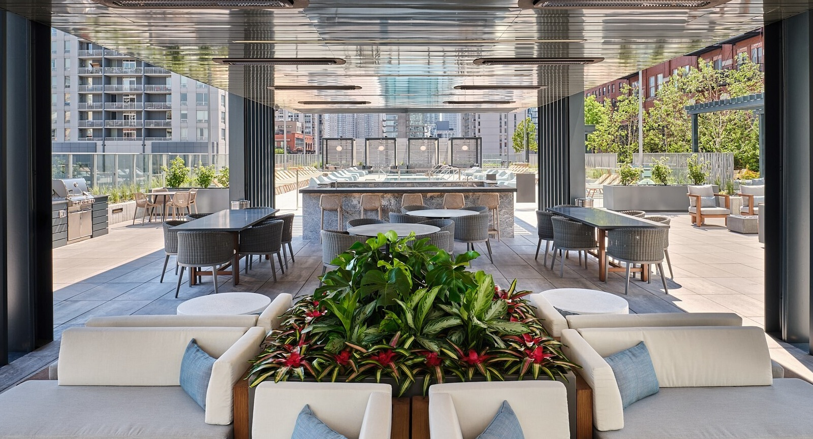 Shaded outdoor pavilion with cushioned seating, dining areas, and a central bar overlooking the pool at 369 Grand apartments in Chicago