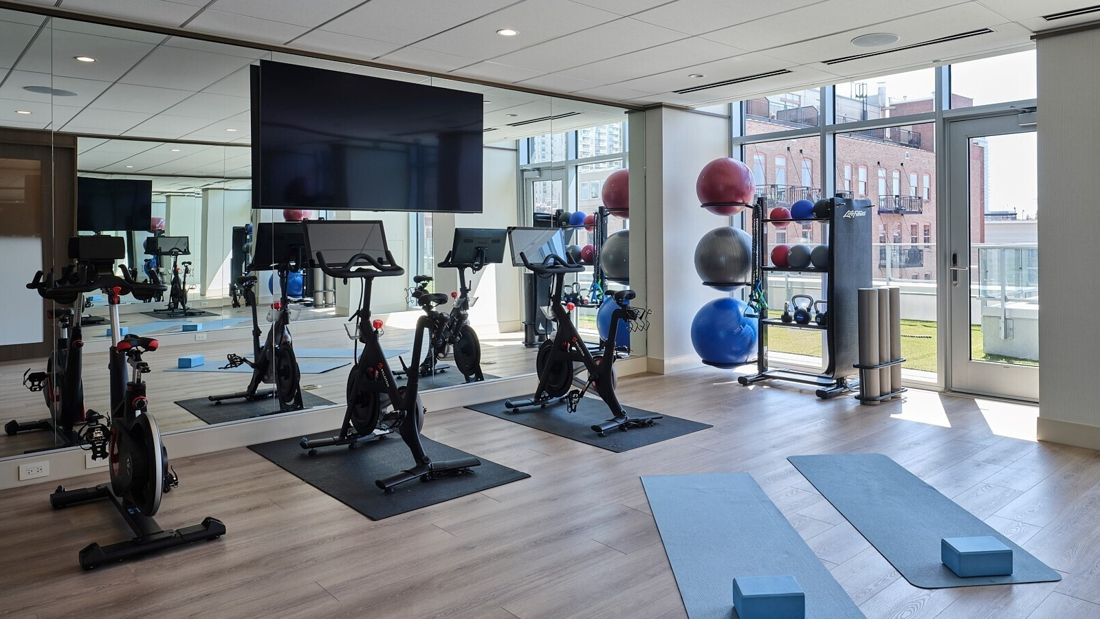 Light-filled yoga and spin studio with stationary bikes, mirrored wall, and mats ready for classes at 369 Grand apartments in Chicago