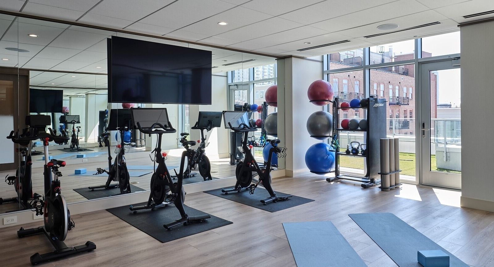Light-filled yoga and spin studio with stationary bikes, mirrored wall, and mats ready for classes at 369 Grand apartments in Chicago